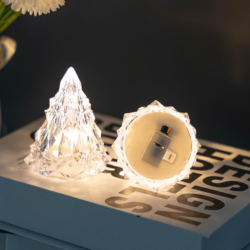 Two LED Crystal Christmas Tree Night Lights shaped like a mountain and a light bulb on a magazine.
